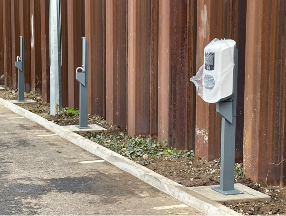 A row of electric charging points next to a fence.